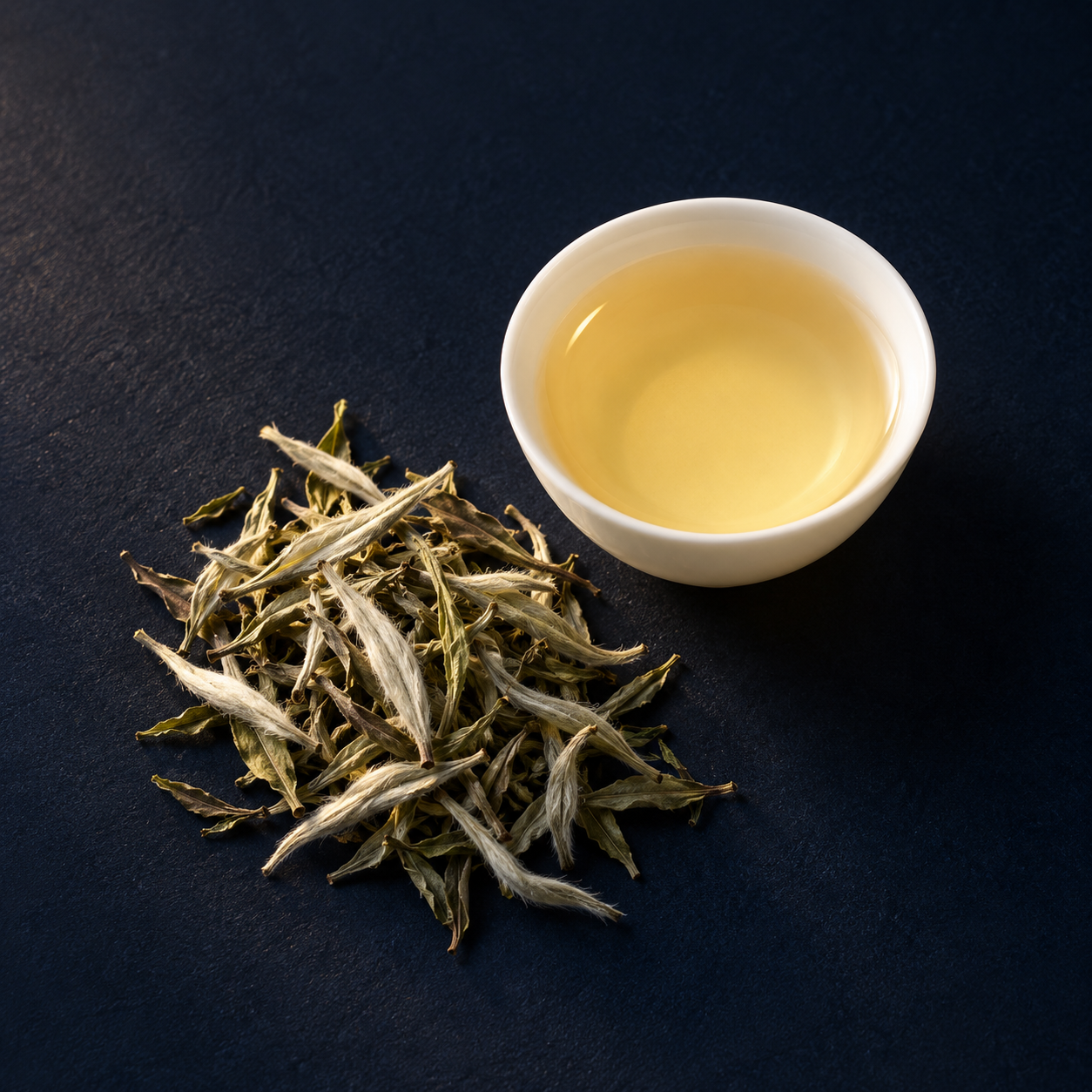 白茶示意：灰綠色乾茶葉與銀白芽毫，搭配淺蜜黃色茶湯